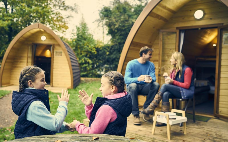 Family sitting outside a glamping Pod at Whitemead Forest Park